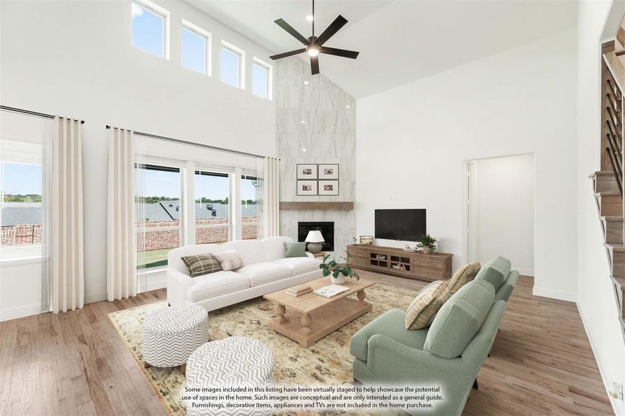 Living room with two-story ceiling, marble fireplace, ceiling fan, and hardwood floors