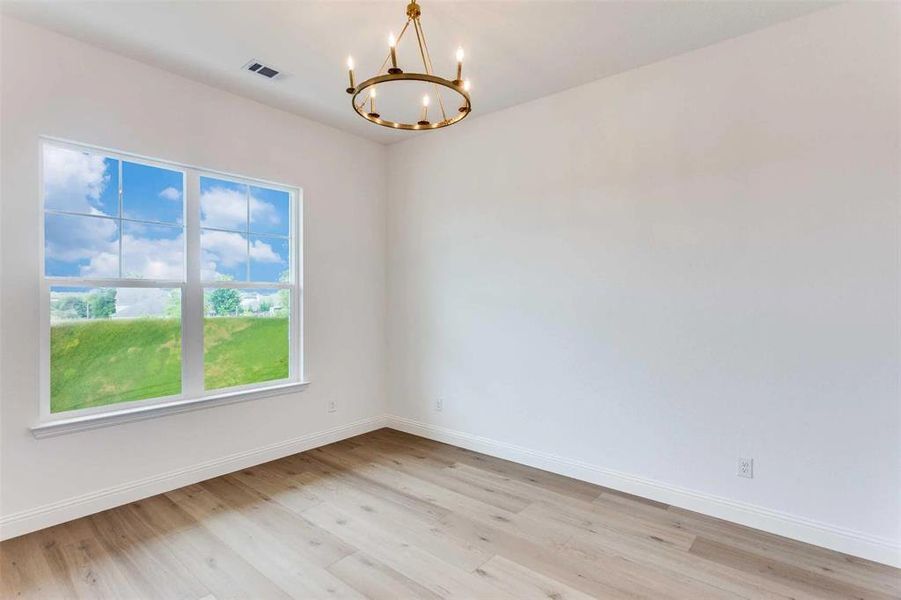 Spare room featuring light wood-style flooring and a chandelier