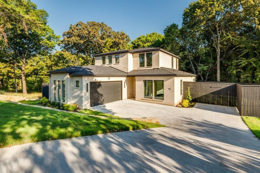 View of front of home with driveway, brick siding, and a gate View of front of home with driveway, brick siding, and a gate