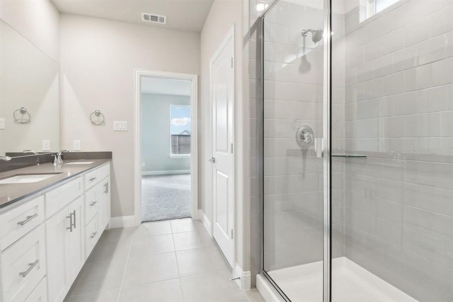 Bathroom featuring tile patterned floors, vanity, and a shower with shower door