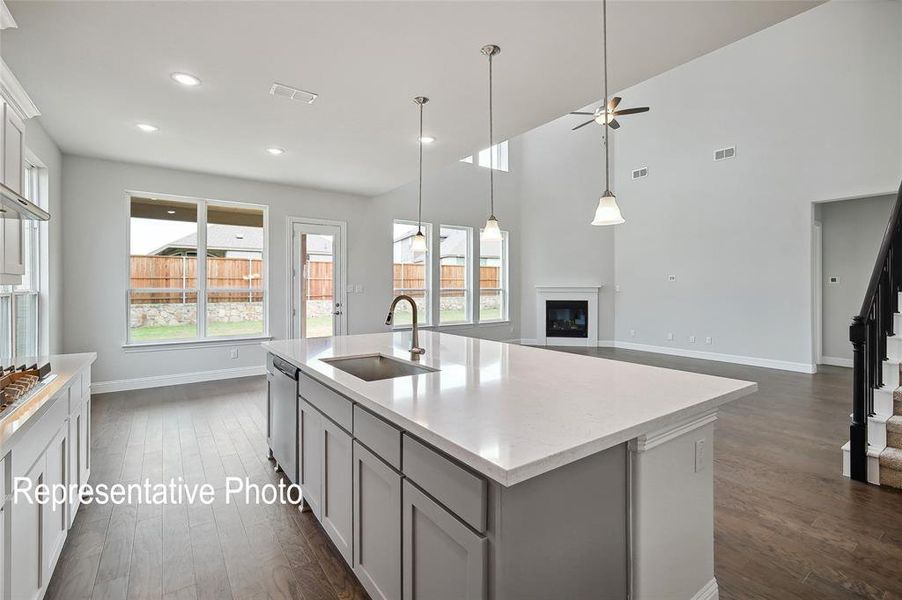 Open-concept living space featuring a central kitchen island with a built-in sink and pendant lighting