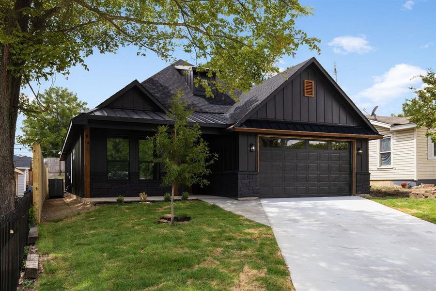 View of front of house featuring a garage, a front yard, and central air condition unit