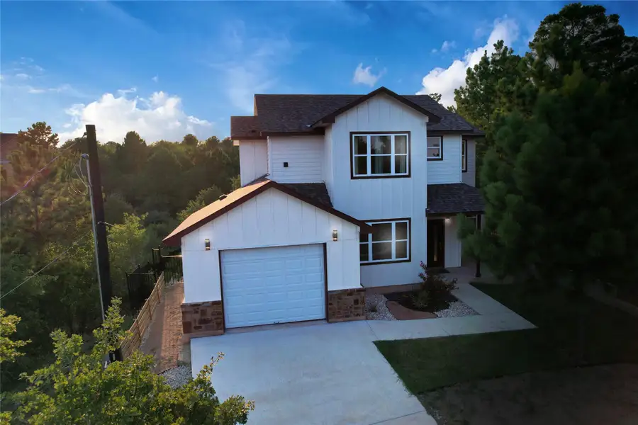 A very welcoming view of front of home with a shingled roof, an attached garage, board and batten siding, driveway, and stone siding. This is 108 Kimo Ct.