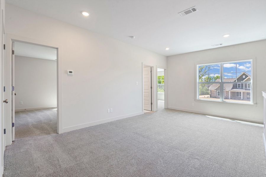 Empty room with light carpet and recessed lighting
