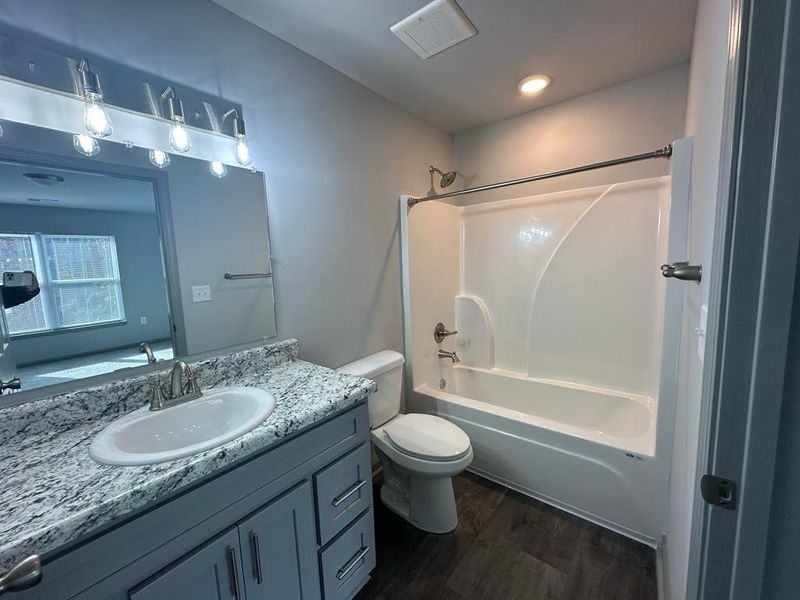 Full bathroom with toilet, bathtub / shower combination, oversized vanity, and hardwood / wood-style floors