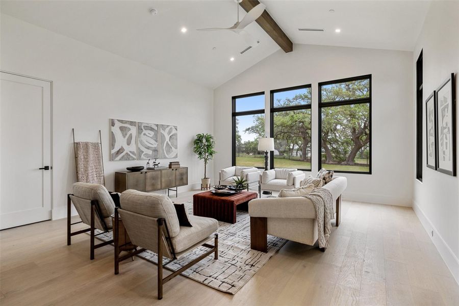 Living area featuring beamed ceiling, baseboards, light wood-style flooring, high vaulted ceiling, and ceiling fan Living area featuring beamed ceiling, baseboards, light wood-style flooring, high vaulted ceiling, and ceiling fan