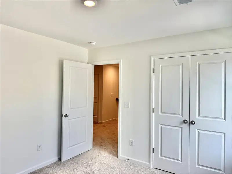 A spacious bedroom features neutral-toned carpet f