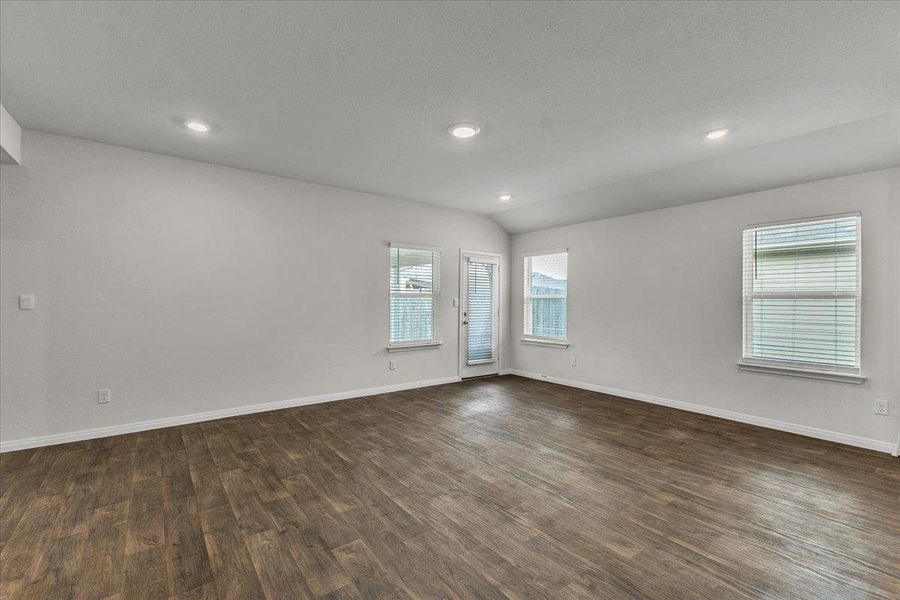 Spacious interior with wood-look flooring, recessed lighting, and multiple windows with blinds
