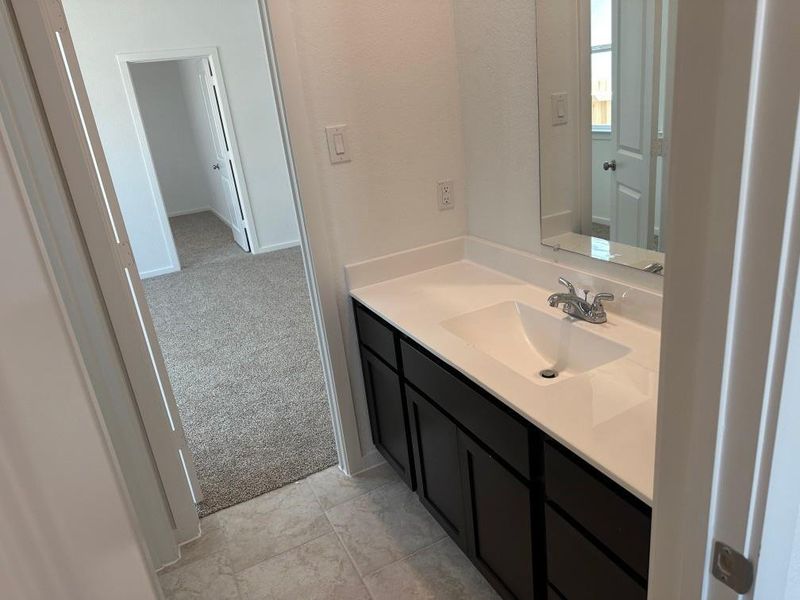 Bathroom with vanity, light colored carpet, and light tile patterned flooring