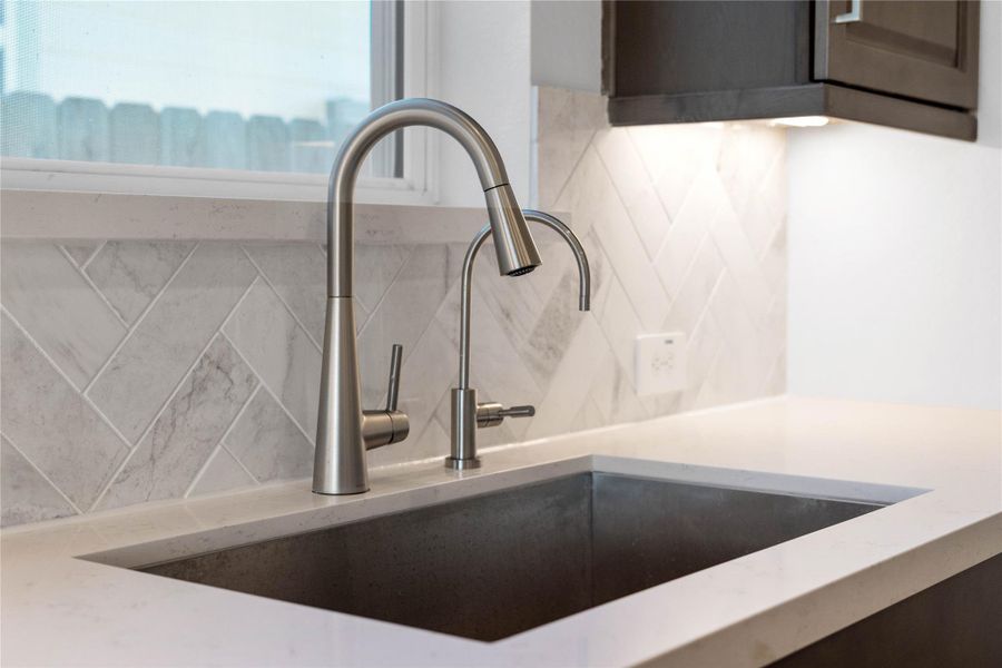 The modern stainless steel undermount sink is perfectly situated beneath a bright window, offering a pleasant view of the outdoors. The modern stainless steel undermount sink is perfectly situated beneath a bright window, offering a pleasant view of the outdoors.