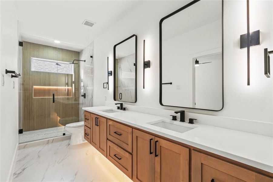 Bathroom with double vanity, a shower stall, and light marble finish flooring