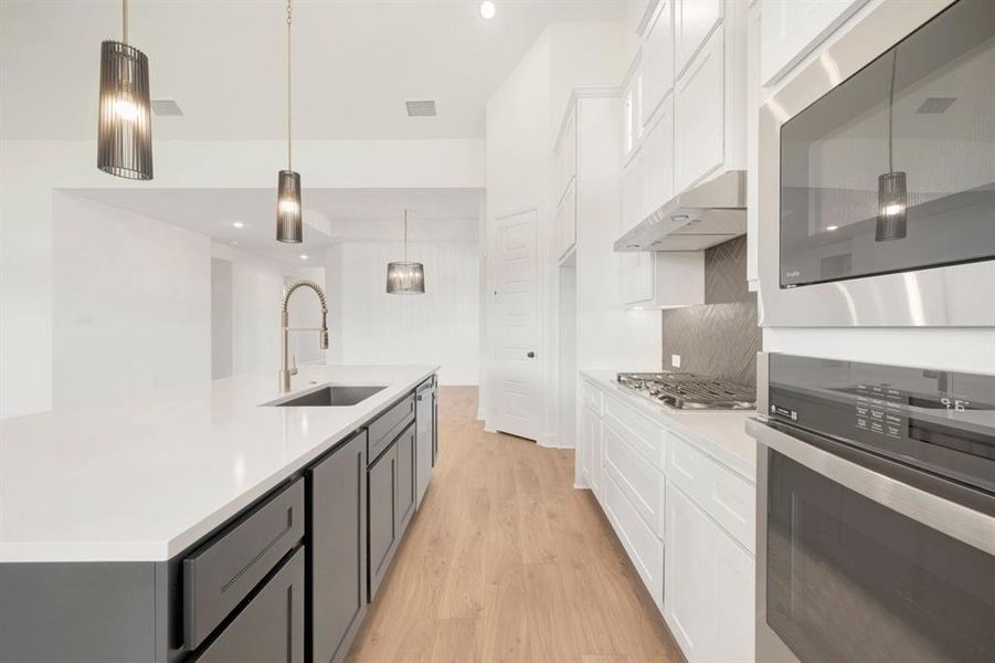 Modern kitchen featuring an extended island with a built-in sink and faucet, complemented by two-tone cabinetry Modern kitchen featuring an extended island with a built-in sink and faucet, complemented by two-tone cabinetry