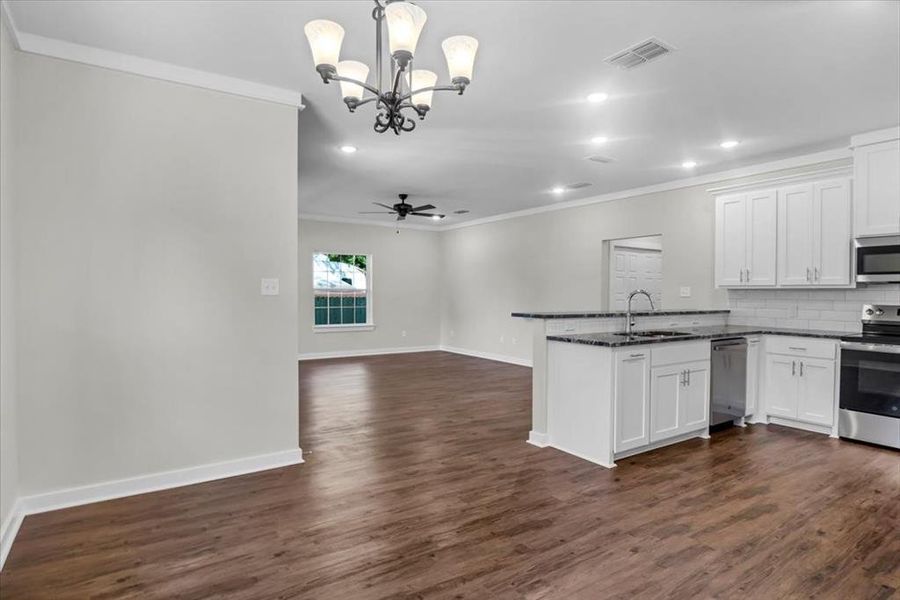 Kitchen with appliances with stainless steel finishes, a sink, crown molding, a peninsula, and a chandelier