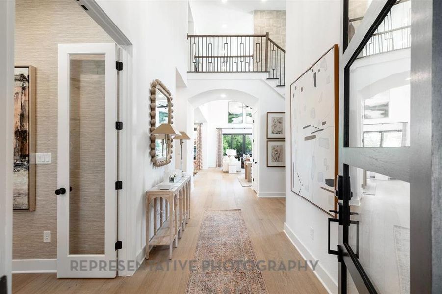 Entryway featuring light wood-style floors, arched walkways, and a towering ceiling Entryway featuring light wood-style floors, arched walkways, and a towering ceiling