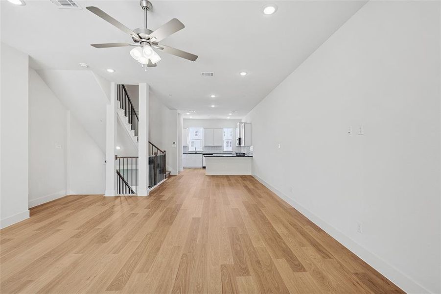 Unfurnished living room featuring light wood-style flooring, ceiling fan, and recessed lighting
