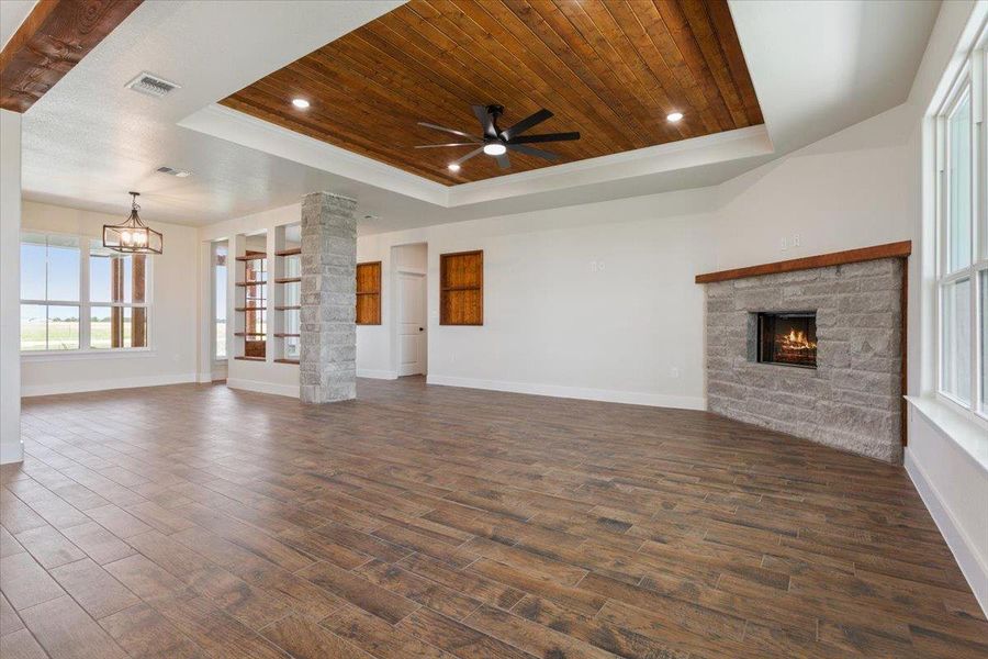 An inviting great room with wood-planked tile flooring and a focal fireplace framed in natural stone.