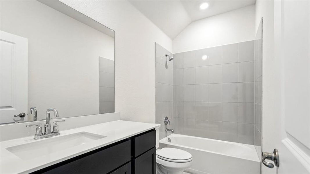 Bathroom with vanity, bathtub / shower combination, and vaulted ceiling