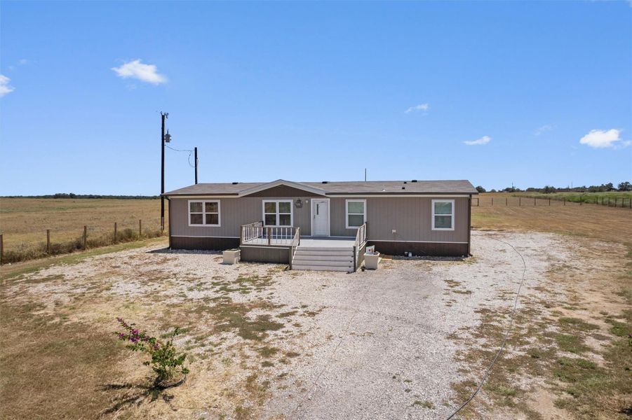 An inviting front porch leads into this manufactured home set against a wide rural horizon.