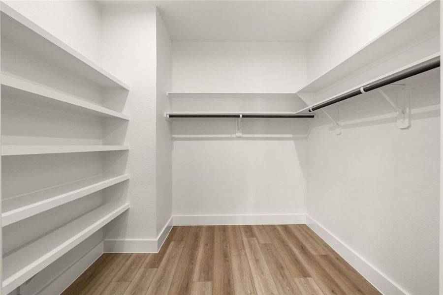 Walk-in closet with built-in shelving, hanging rods, and ample space throughout Walk-in closet with built-in shelving, hanging rods, and ample space throughout