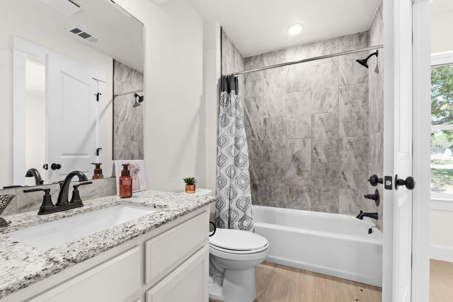 Full bathroom with vanity, shower / bathtub combination with curtain, and light wood-style flooring