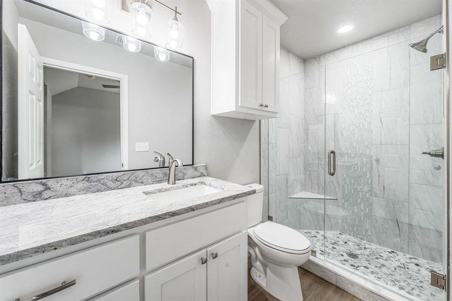 Bathroom featuring a shower stall, vanity, wood finished floors, and toilet Bathroom featuring a shower stall, vanity, wood finished floors, and toilet