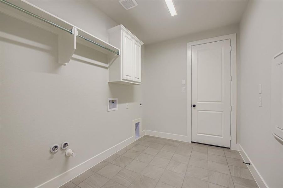 Laundry area with washer hookup, electric dryer hookup, cabinet space, hookup for a gas dryer, and light tile patterned floors
