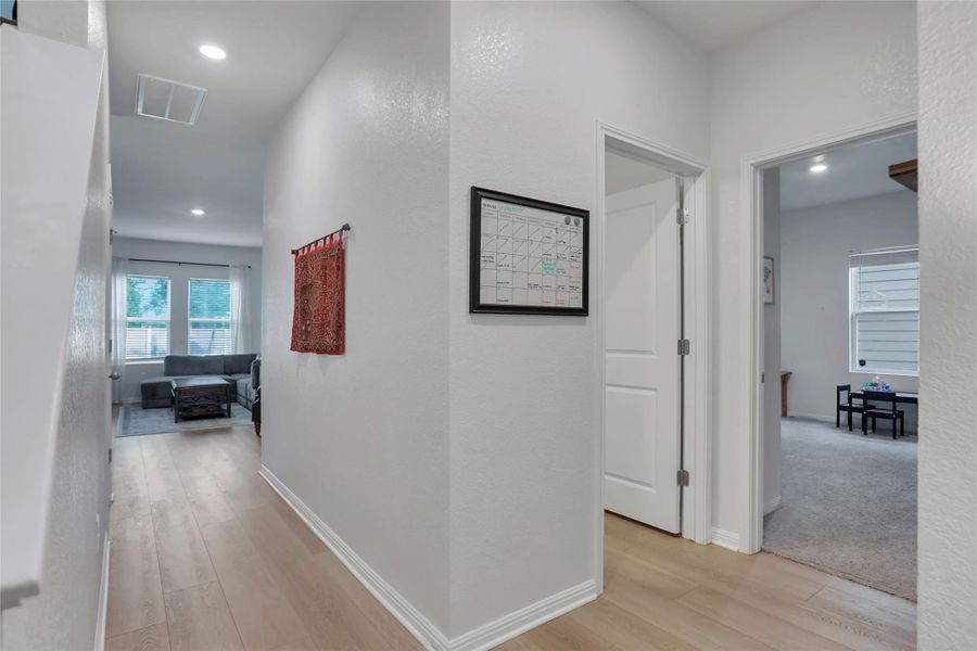 Hallway with light wood finished floors, recessed lighting, and a textured wall