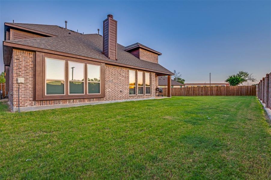 Back of property featuring a shingled roof, a chimney, a fenced backyard, and brick siding Back of property featuring a shingled roof, a chimney, a fenced backyard, and brick siding