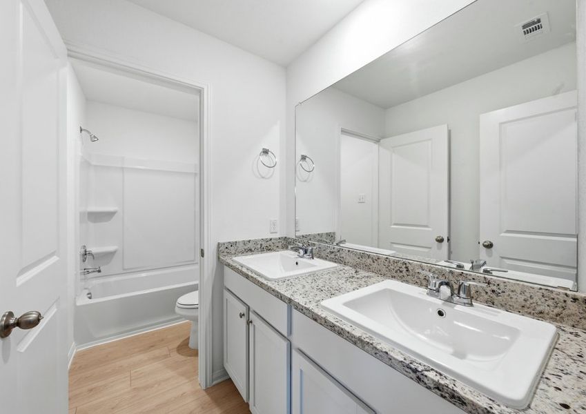 Secondary bathroom featuring a double vanity with granite countertop and a tub/shower combination. Secondary bathroom featuring a double vanity with granite countertop and a tub/shower combination.