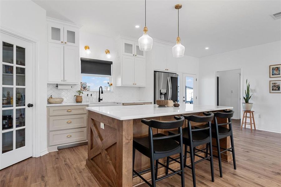 Kitchen with a center island, a kitchen breakfast bar, light wood finished floors, tasteful backsplash, and recessed lighting