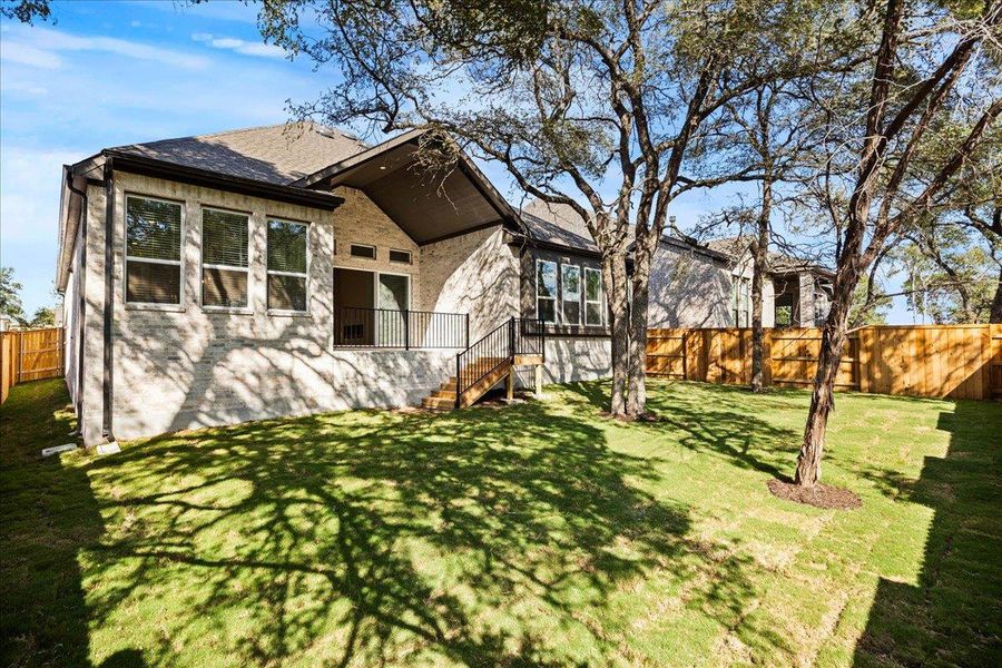 Rear view of house with a fenced backyard, brick siding, and a shingled roof