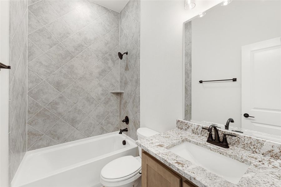 Bathroom with tub-shower combo, diagonal gray tile walls, granite vanity, and dark bronze fixtures