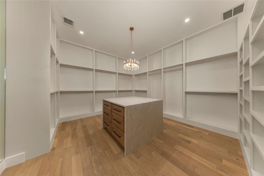 Walk in closet featuring light wood-style floors and a chandelier