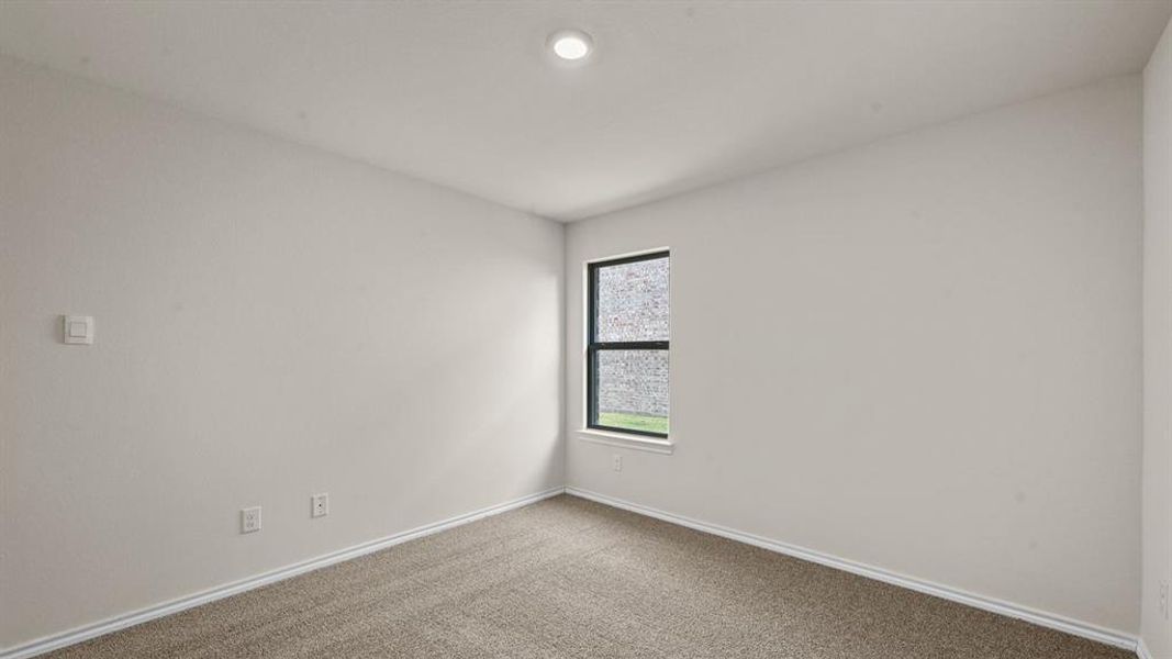 Neutral-toned carpeted room featuring a single window with black trim, recessed ceiling lighting, and light-colored walls Neutral-toned carpeted room featuring a single window with black trim, recessed ceiling lighting, and light-colored walls