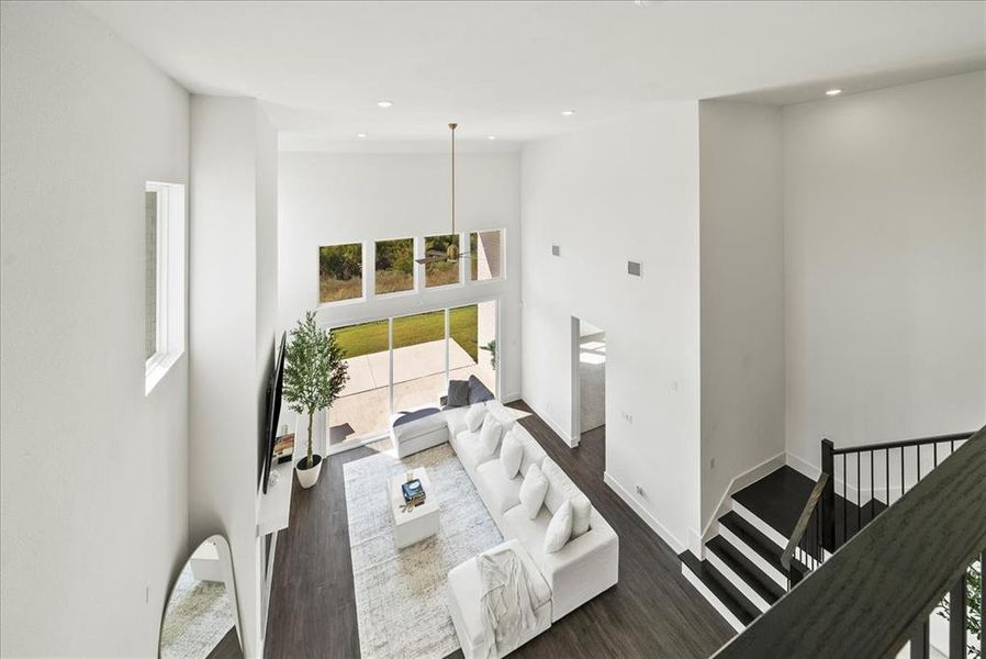 Living room with baseboards, a high ceiling, dark wood finished floors, and recessed lighting