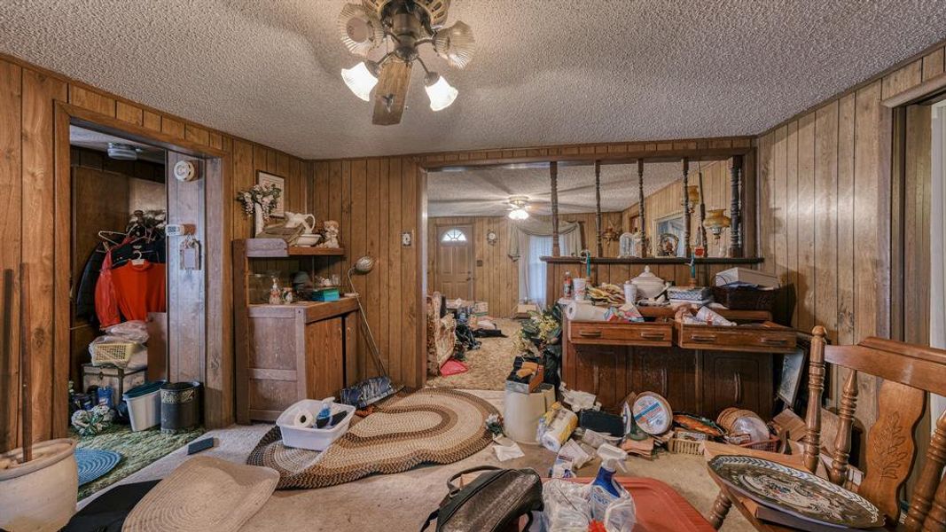 Misc room with carpet flooring, a textured ceiling, ceiling fan, and wooden walls