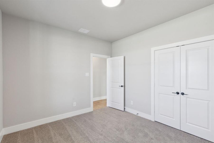 Unfurnished bedroom featuring a closet, baseboards, visible vents, and carpet flooring