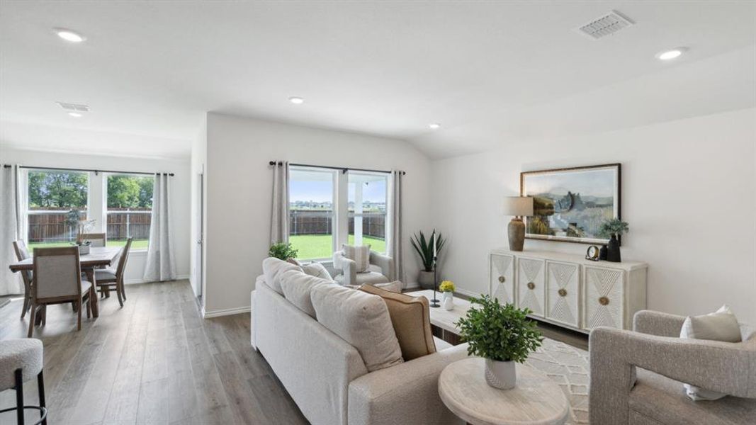 Living room with plenty of natural light, lofted ceiling, wood finished floors, and recessed lighting