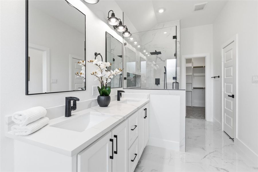 Full bathroom featuring double vanity, a marble finish shower, a walk in closet, and light marble finish floors