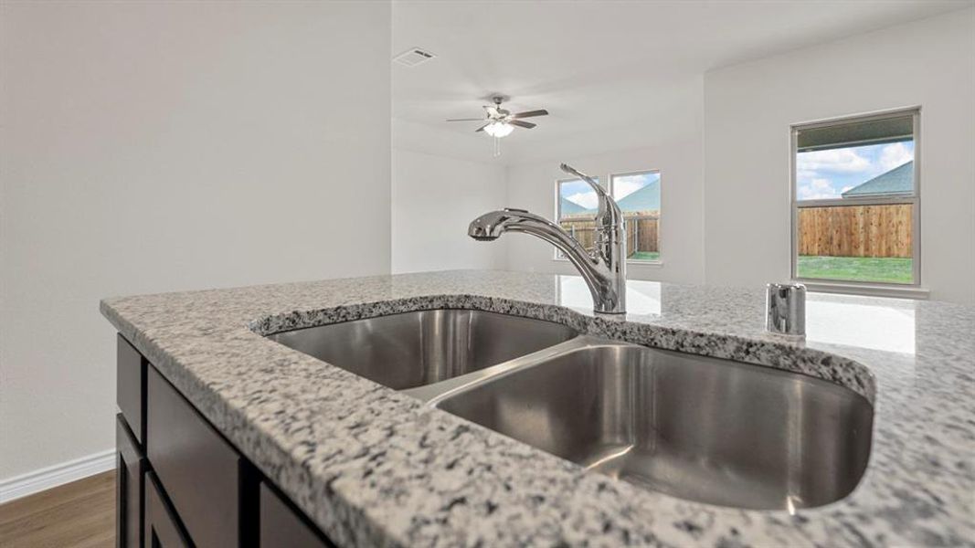 Kitchen island featuring a dual stainless steel sink, granite countertop, and chrome gooseneck faucet