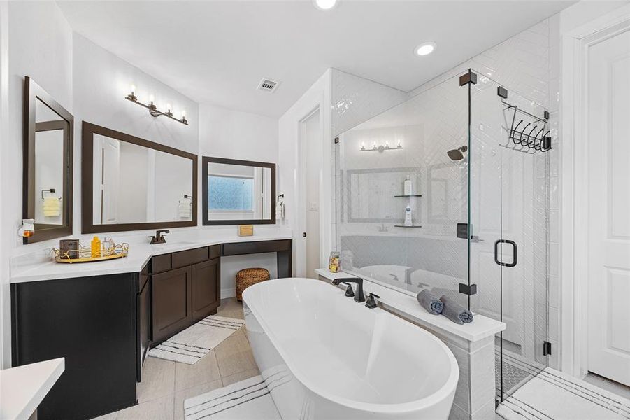Full bathroom featuring tile patterned flooring, vanity, a freestanding tub, visible vents, and a stall shower