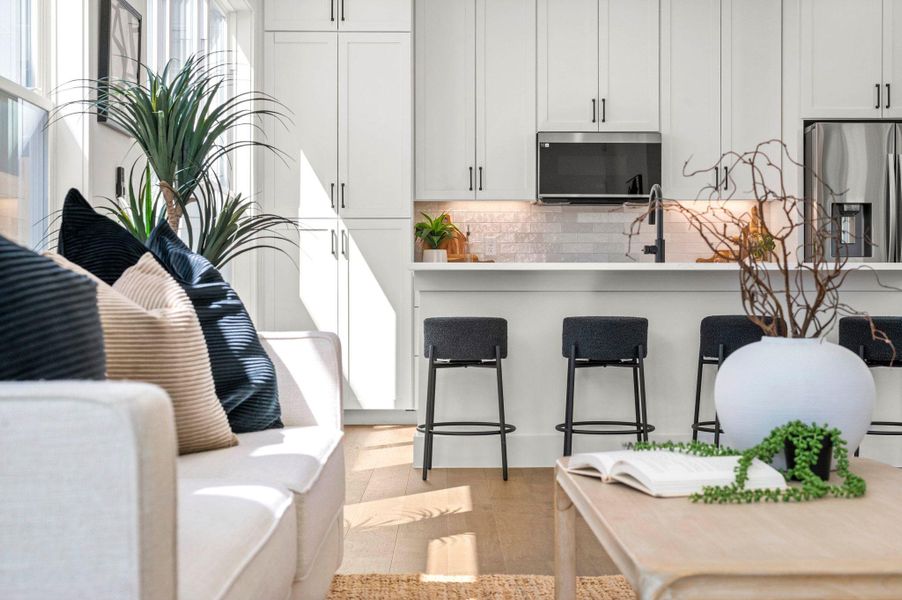 Kitchen with stainless steel appliances, a breakfast bar, white cabinets, and tasteful backsplash