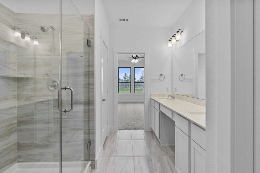 Image of a primary bathroom with a standing walk-in shower with glass doors, a jack and jill vanity and a large mirror Image of a primary bathroom with a standing walk-in shower with glass doors, a jack and jill vanity and a large mirror