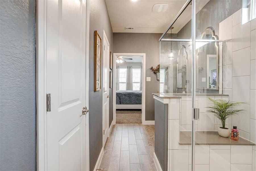 Ensuite bathroom featuring visible vents, a ceiling fan, a stall shower, connected bathroom, and wood finished floors