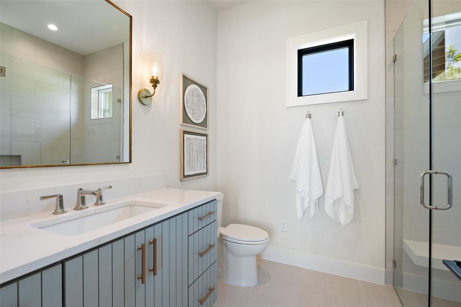 Full bath with a shower stall, plenty of natural light, vanity, and light tile patterned flooring