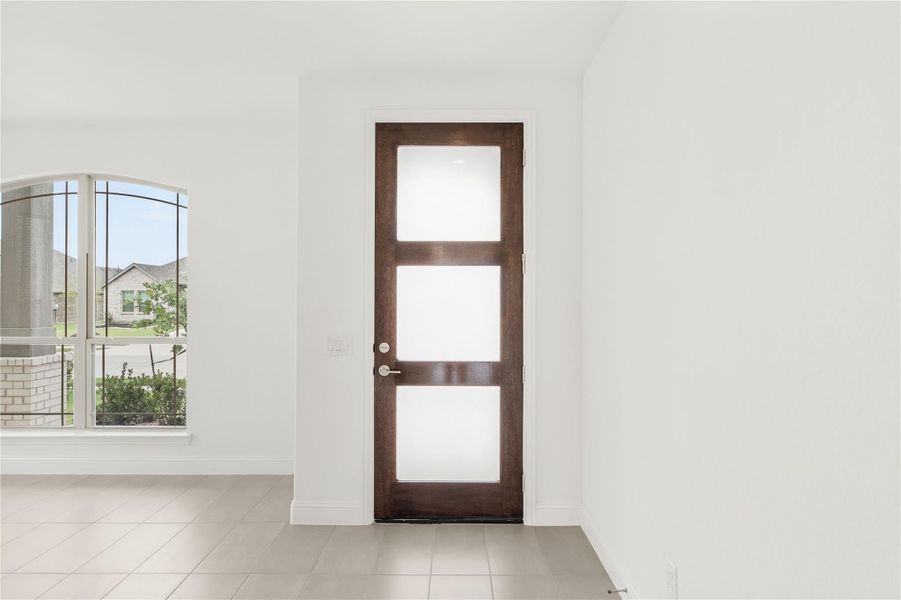 Dark wood interior door with three frosted glass panels in a white room with tile floors and arched window. Dark wood interior door with three frosted glass panels in a white room with tile floors and arched window.