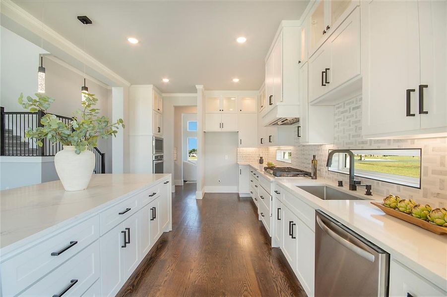 Kitchen featuring white cabinets, stainless steel appliances, decorative light fixtures, tasteful backsplash, and dark wood finished floors Kitchen featuring white cabinets, stainless steel appliances, decorative light fixtures, tasteful backsplash, and dark wood finished floors