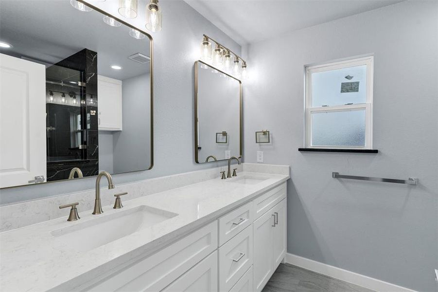 Full bathroom with baseboards and double vanity