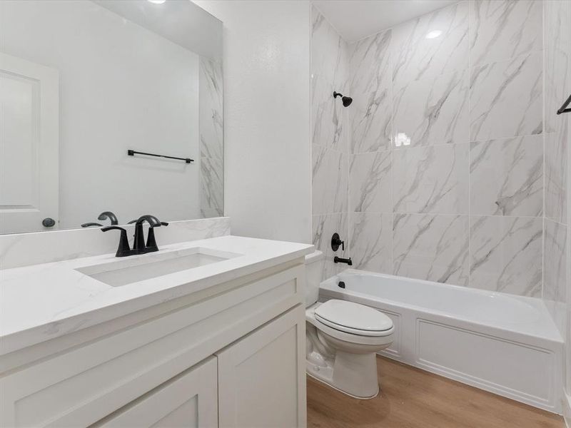 Full bath with shower / tub combination, vanity, and light wood-style floors