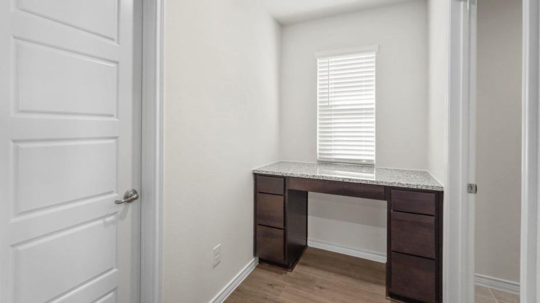 Built-in desk featuring a granite-finish countertop, dark wood-finish cabinetry, and multiple drawers